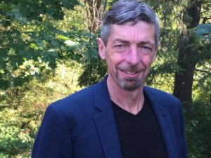 Portrait of Dean Nicholson smiling in a lush forest, reflecting calm presence, mindfulness, and Clear Sky Center teachings